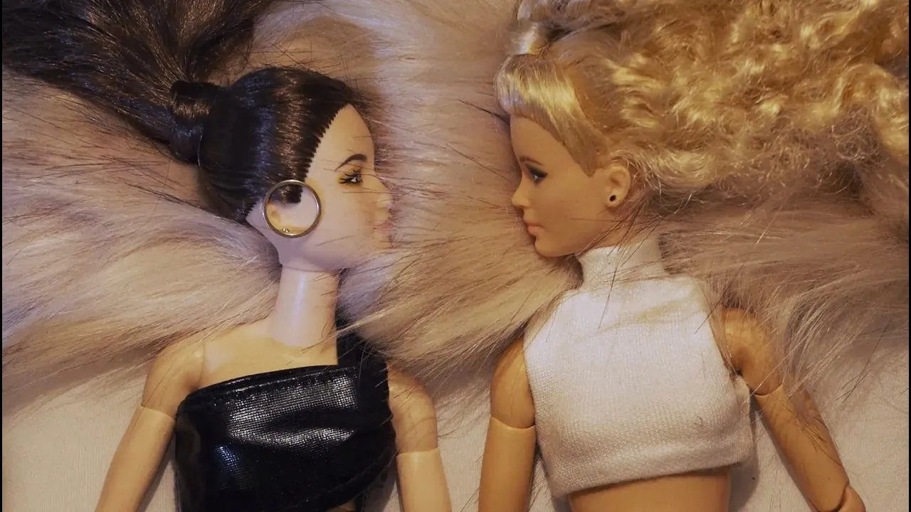still from the kill 2 video: two fashion dolls lying on white fur